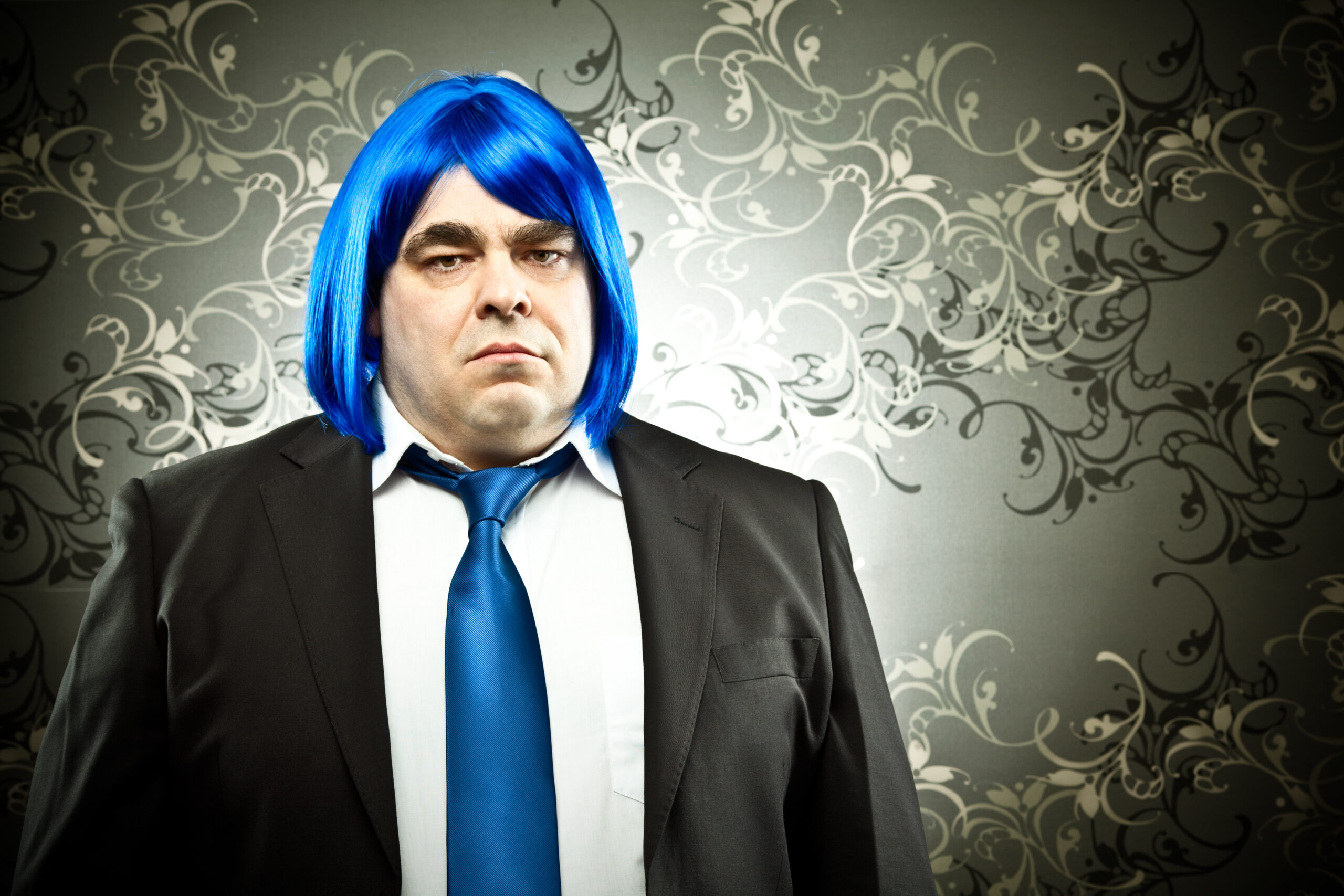businessman with colored tie and hair wig on tapestry background
